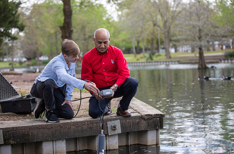 student and professor testing soil from river
