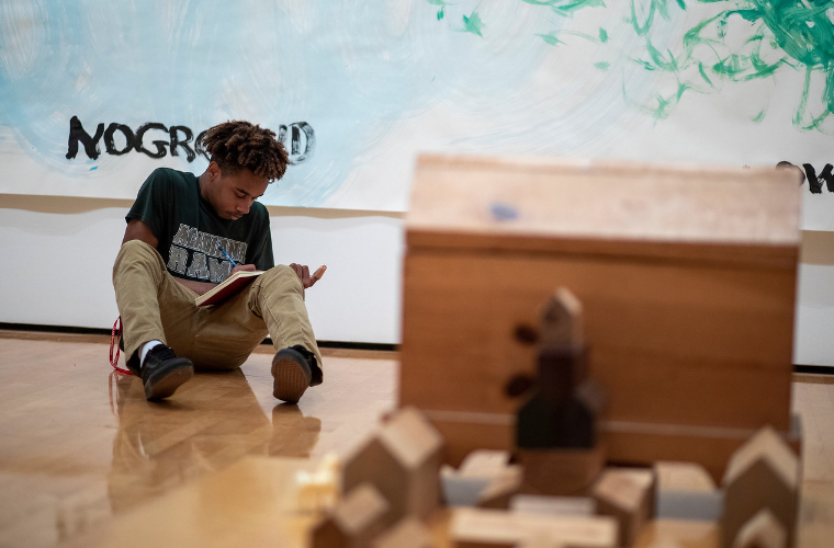 UL Lafayette student writes while sitting on floor of art museum