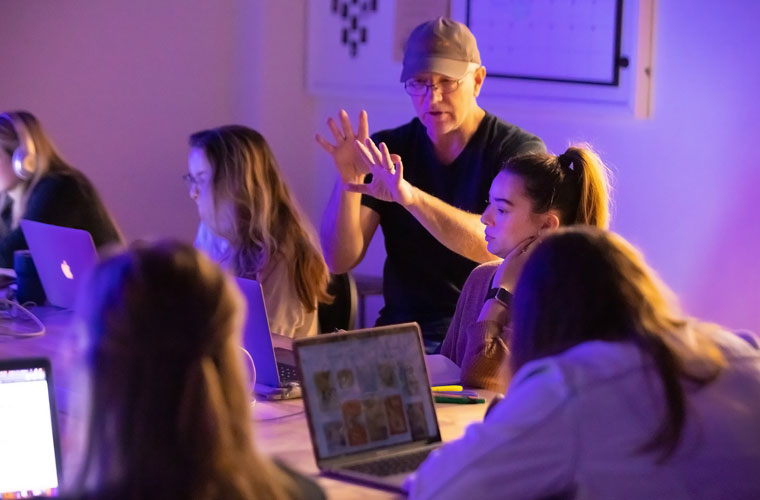Graphic design students at the University of Louisiana at Lafayette sit around a table during a critique