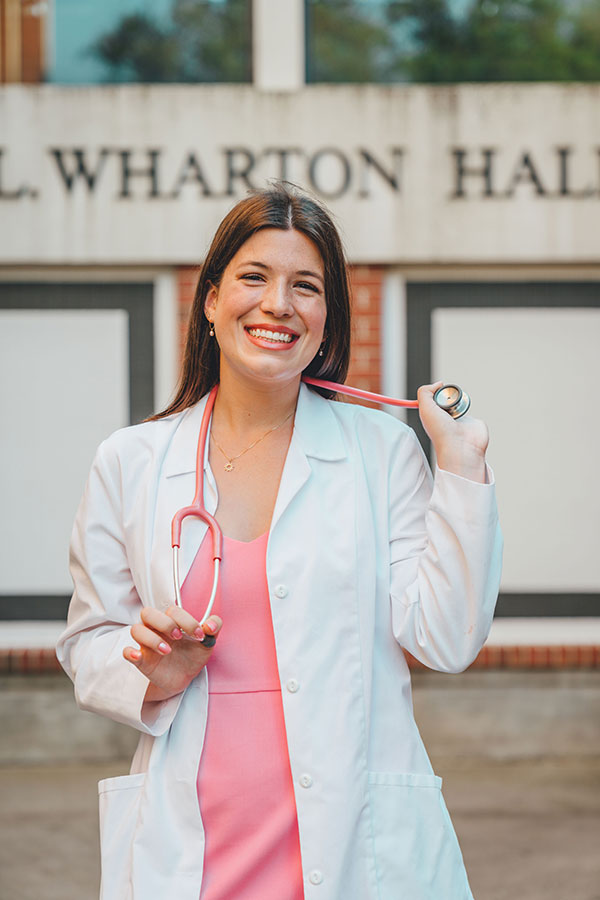 Nursing major and licensed RN Tea Minor in front of the nursing build on UL Lafayette's campus