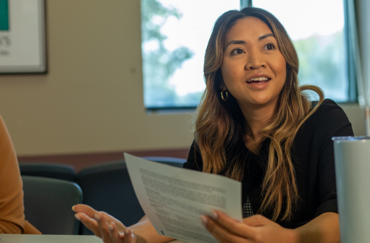 Sally Wilson holds a sheet of paper as she talks during a staff meeting.