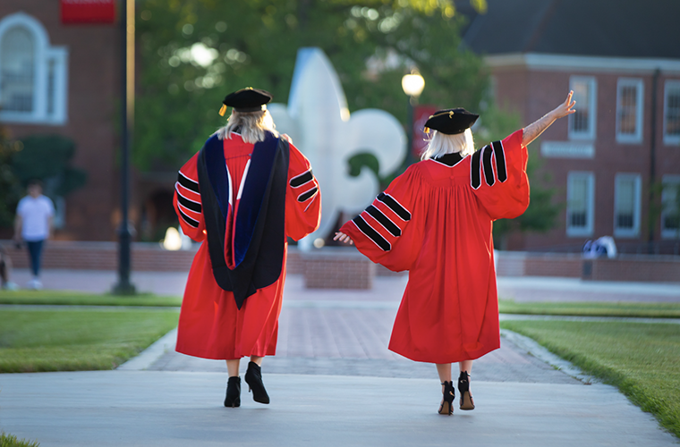 UL Lafayette doctoral graduates walking through the quad in regalia