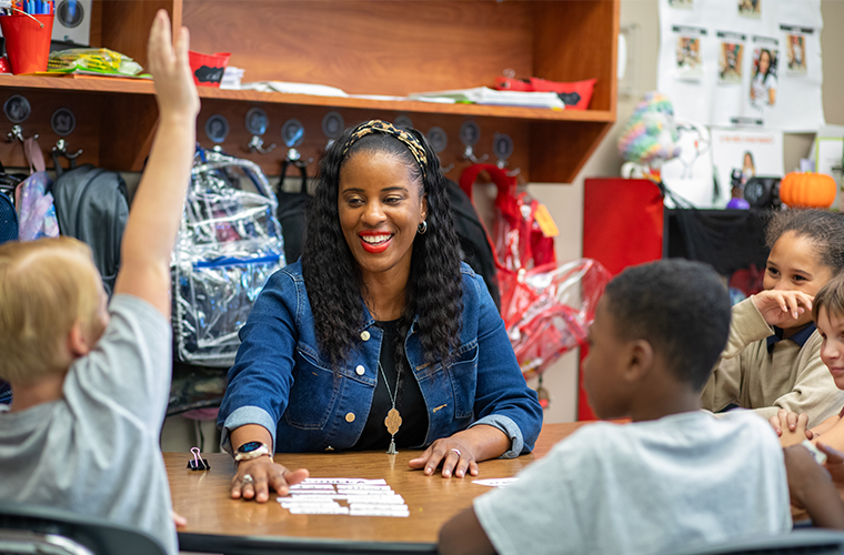 Rekeisha Treig sits with four students at a classroom table.
