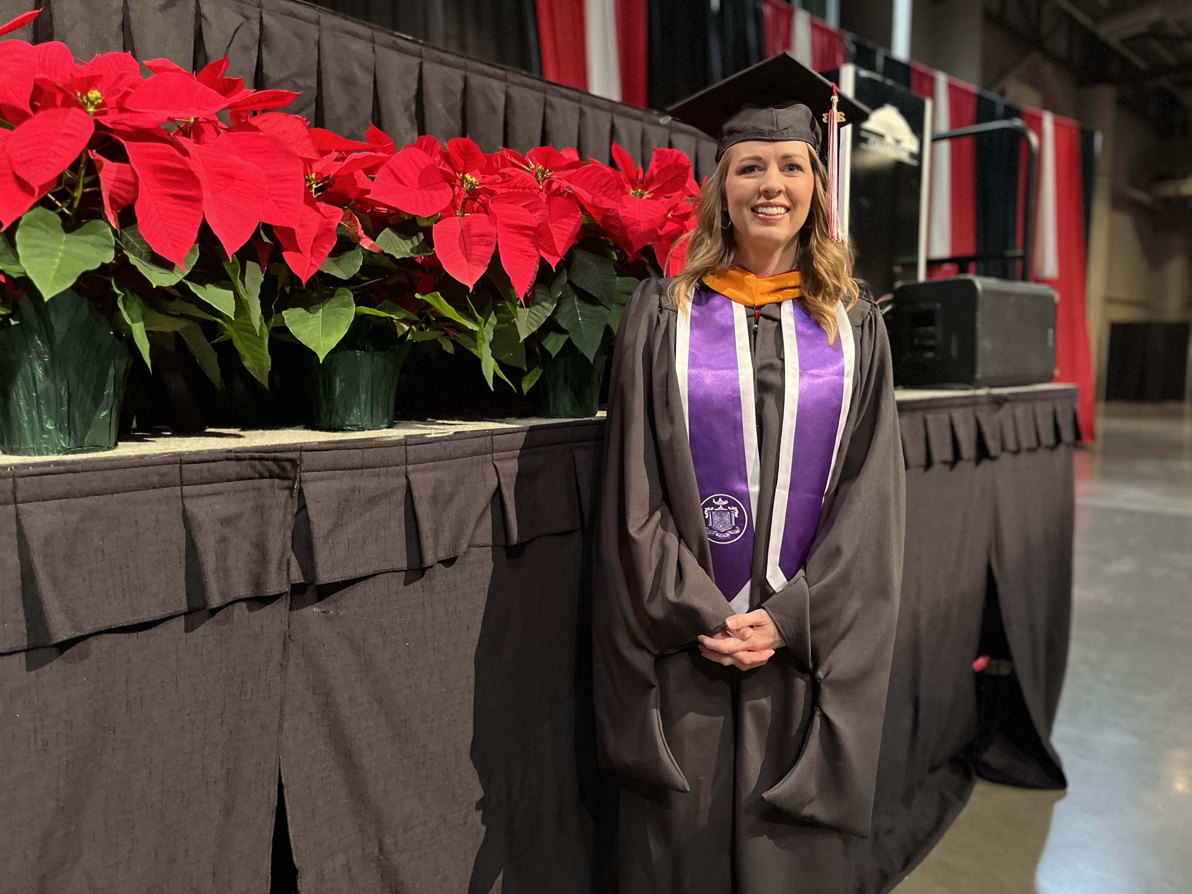 Dana Wallis stands near the commencement stage at the Cajundome Convention Center ahead of Fall 2023 graduation.