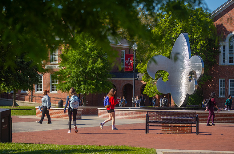 students walking by the Fleur de Lis fountain in the UL Lafayette quad