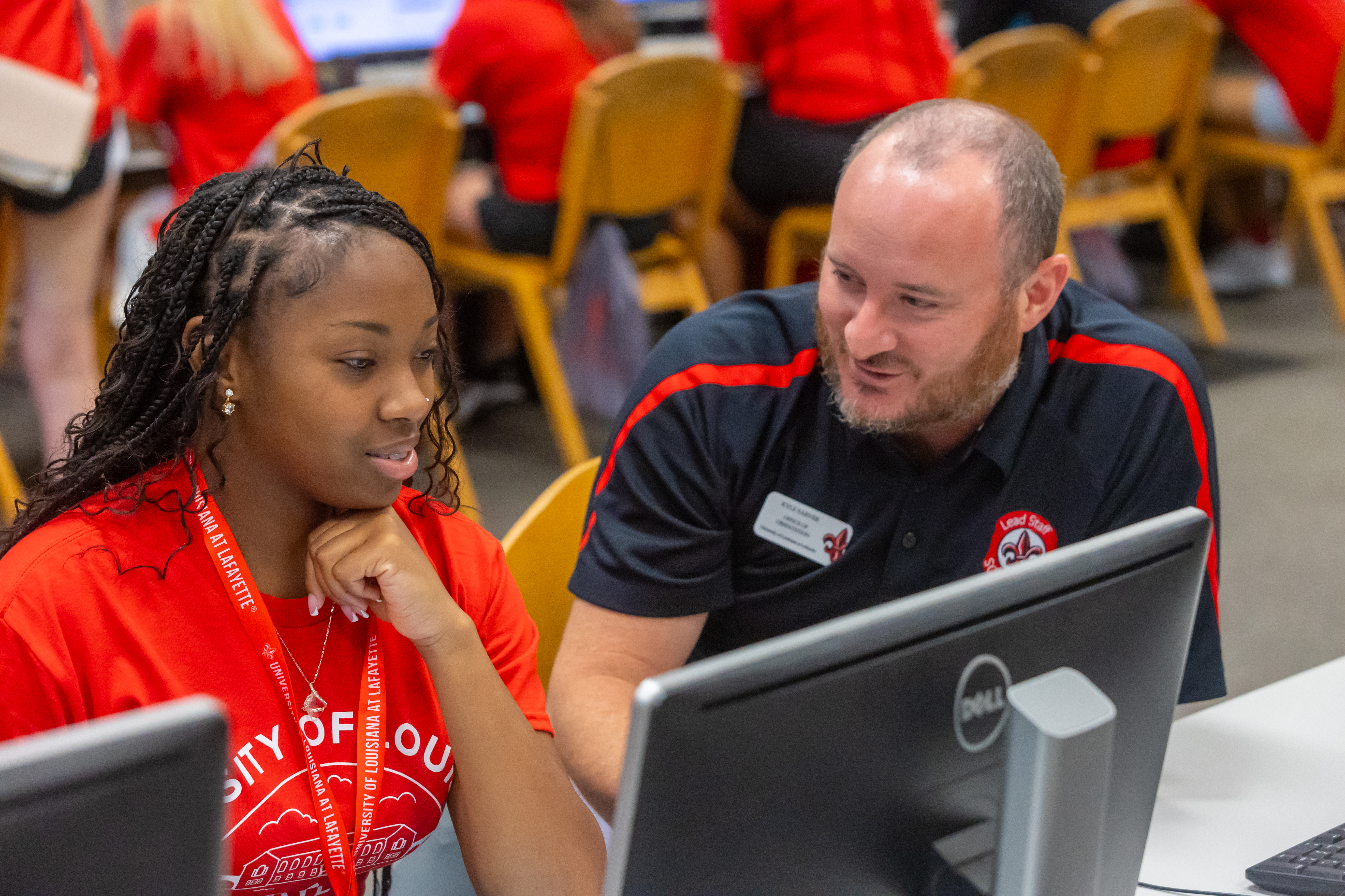 A UL Lafayette staff talks with incoming freshman student in front of a computer monitor in the library