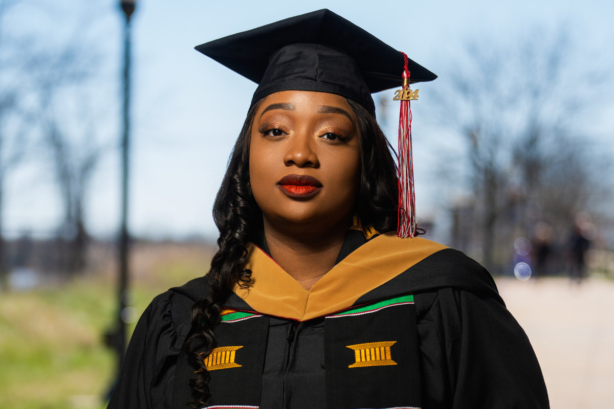 UL Lafayette online MBA grad poses in black graduation regalia. 