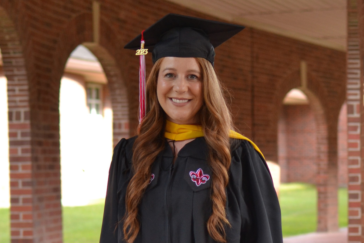 Tori Miguez, graduate of the masters in informatics online program, poses for a cap & gown photo on UL Lafayette's campus.