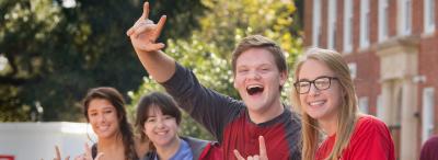 students smiling and making the UL hand sign