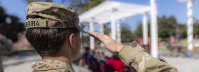 Person pictured shoulder-up from behind in veteran attire, saluting