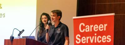 UL Lafayette student government association representative speaking into a microphone at a podium in front of a sign that says "Career Services"