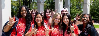 Group of happy UL Lafayette orientation staff holding up "UL" hand signs