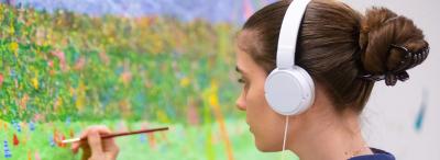 UL student paints flowers in a field on a brighly colored canvas 