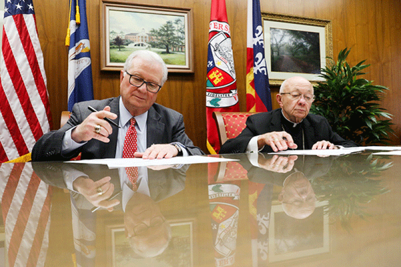 Dr. Joseph Savoie signs agreement with Bishop J. Douglas Deshotel of the Catholic Diocese of Lafayette