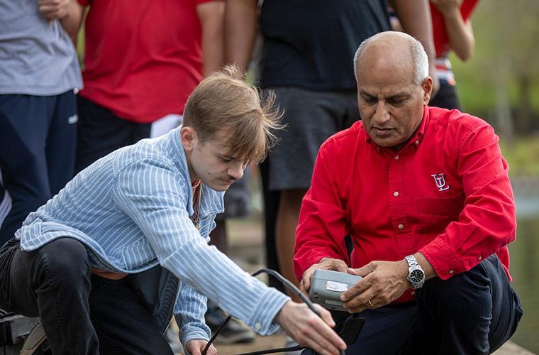 UL student George Bailey collects a water sample with his professor 