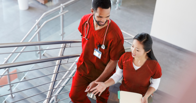 Two online nursing students wearing red scrubs in discussion.