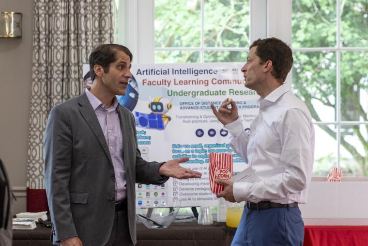 Dr. Francesco Crocco, Assistant Director for Instructional Support, left, is pictured speaking with an attendee during the 2026 FLC Showcase with a presentation board in the background.